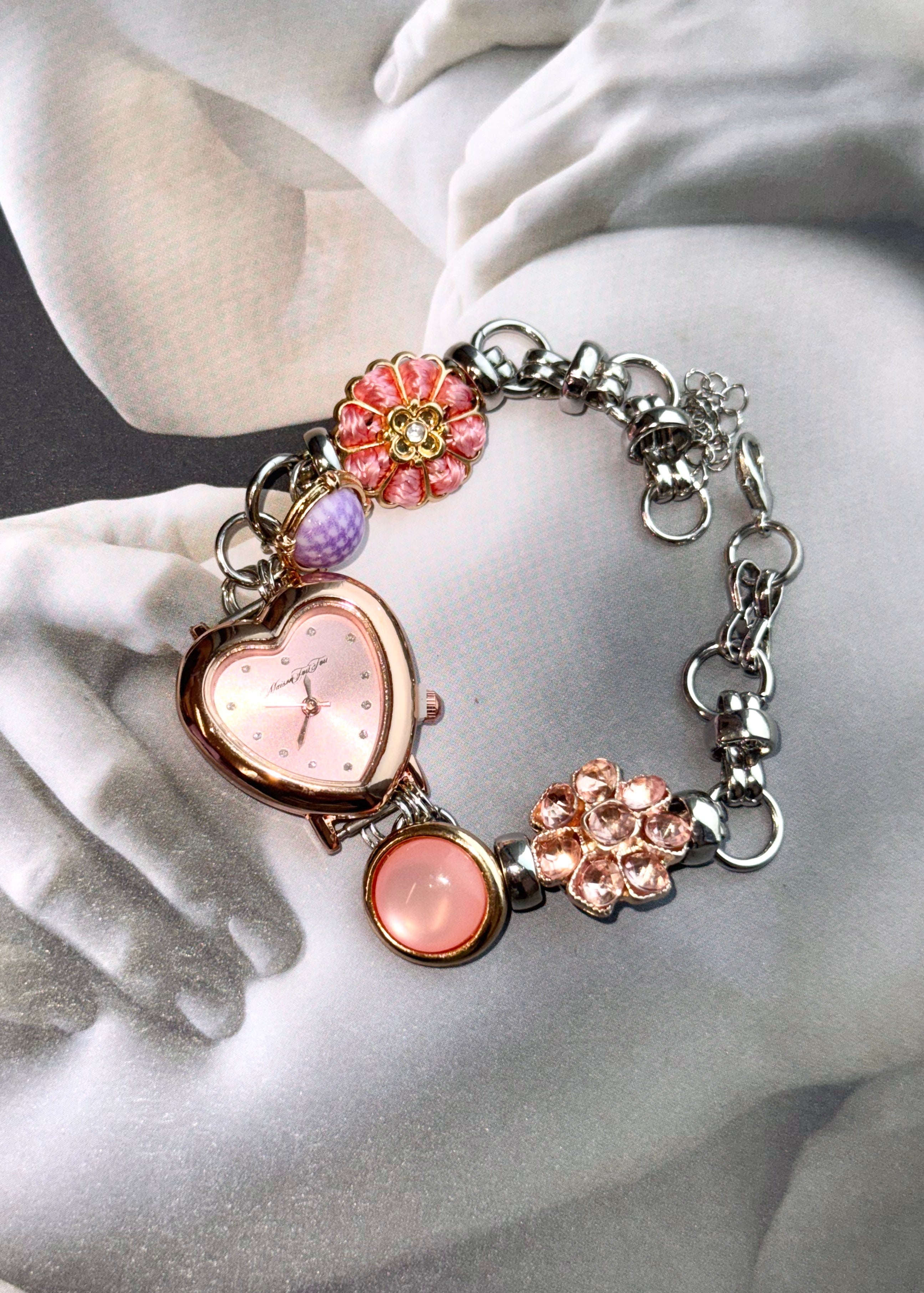Anastasia O'Clock Bracelet with decorative elements on a white marble surface, colored stone heart flower watch rose golden silver 18k gold plated bracelet