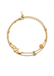 A delicate gold-toned double-strand chain bracelet featuring a crescent moon and star pendant, a small blue gemstone, and a textured gold bead accent, displayed on a clean white background.